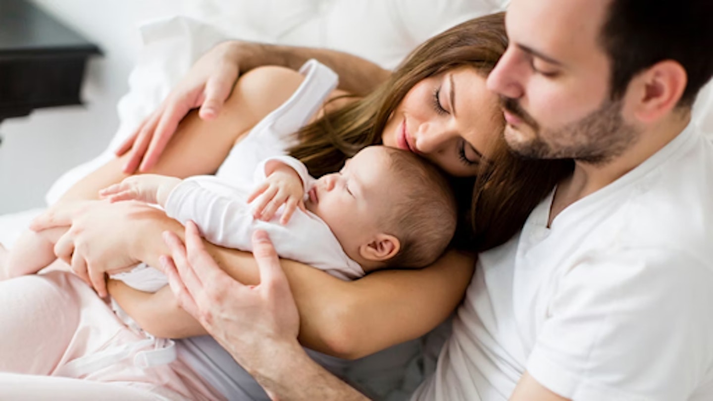 Mum dad and baby in bed