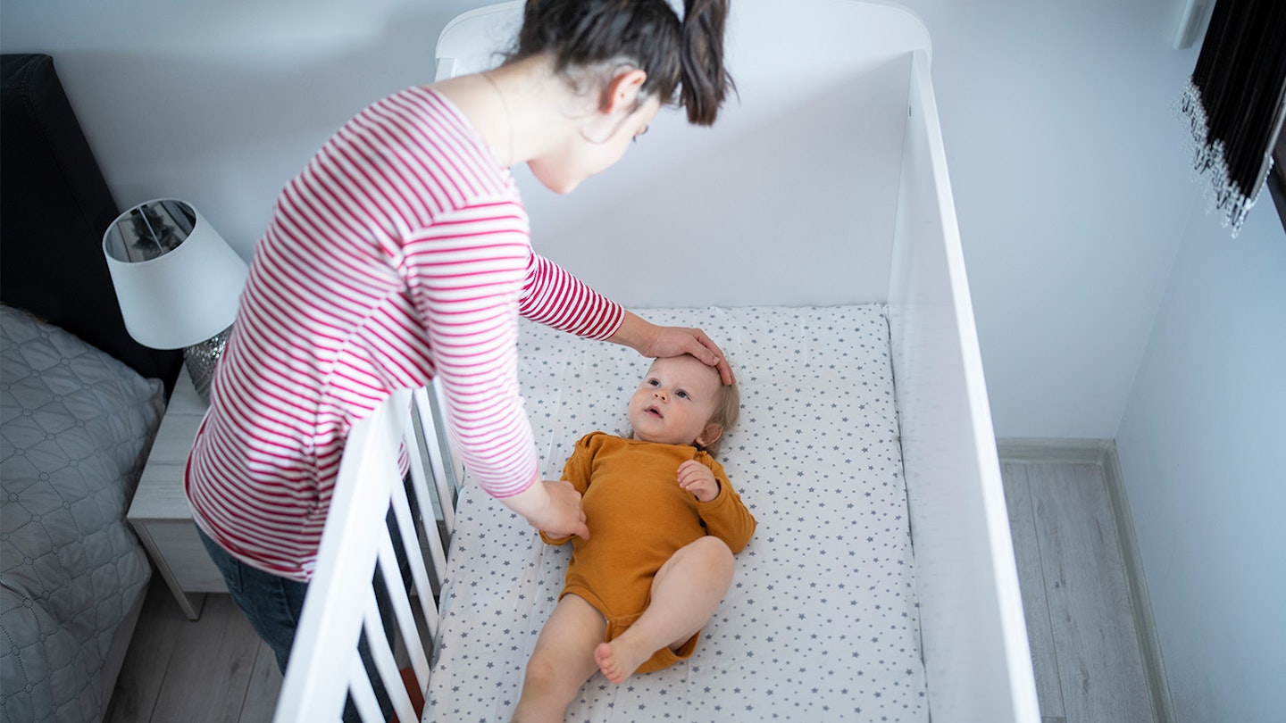 Mum checking baby in cot